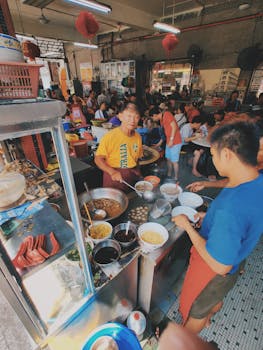 Vibrant scene of locals enjoying traditional street food at a bustling Kuala Lumpur eatery.