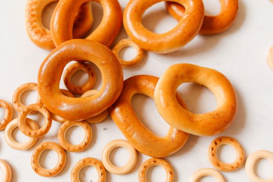Glossy amber bubliki bread rings scattered among small crunchy sushki rings on a white surface