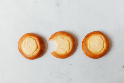 Free Three Russian vatrushki pastries with cream cheese on a white surface, one bitten. Stock Photo