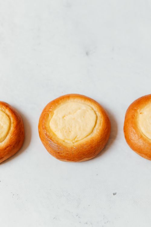 Free Close-up view of baked Russian vatrushki, highlighting their golden crust and creamy filling. Stock Photo