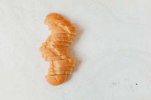 A neatly sliced loaf of white bread arranged on a light marble background.