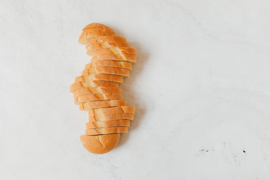 A neatly sliced loaf of white bread arranged on a light marble background.