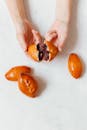 Person Holding Orange Fruit Beside Two Orange Fruits