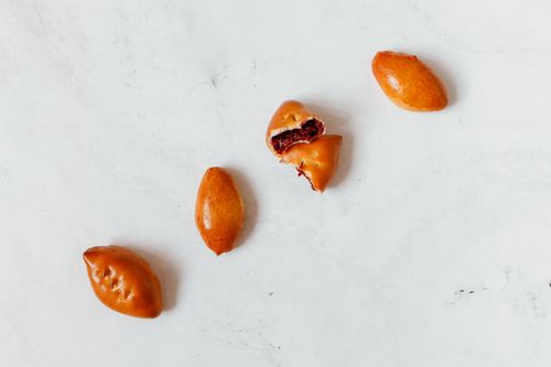 Free Flat lay of traditional Russian pirozhki pastries on a white background, highlighting their golden crust. Stock Photo