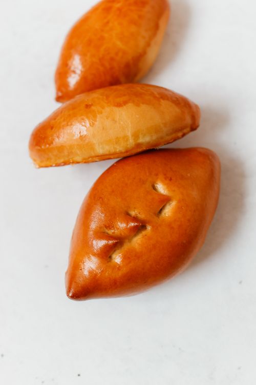 Free Close-up of freshly baked pirozhki showcasing golden-brown crusts on a white surface. Stock Photo