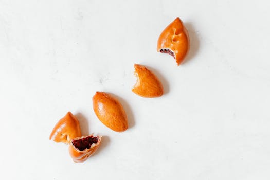 Aerial shot of four Russian piroshki on a white background, showcasing delicious golden-brown pastry.