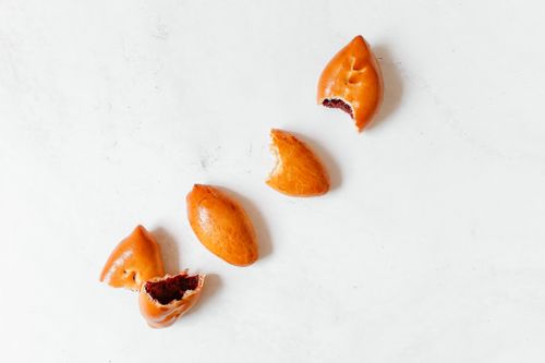 Free Aerial shot of four Russian piroshki on a white background, showcasing delicious golden-brown pastry. Stock Photo
