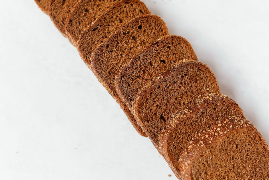Top view of freshly sliced whole wheat bread on a white background, perfect for bakery or food-related projects.