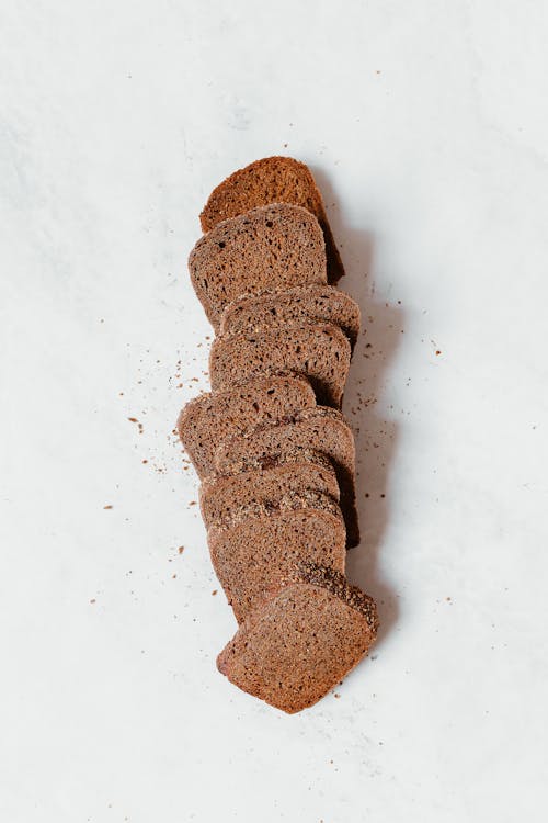 Free Slices of Brown Bread on White Surface Stock Photo