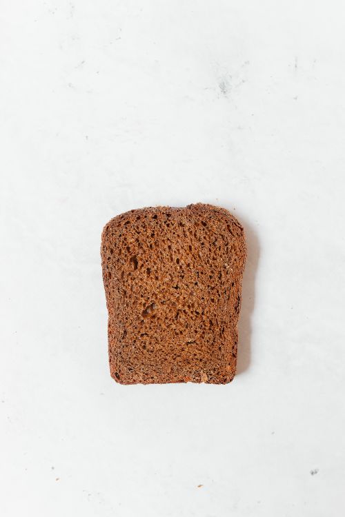 Free Close-up of a single rye bread slice placed on a white surface, minimal setup. Stock Photo