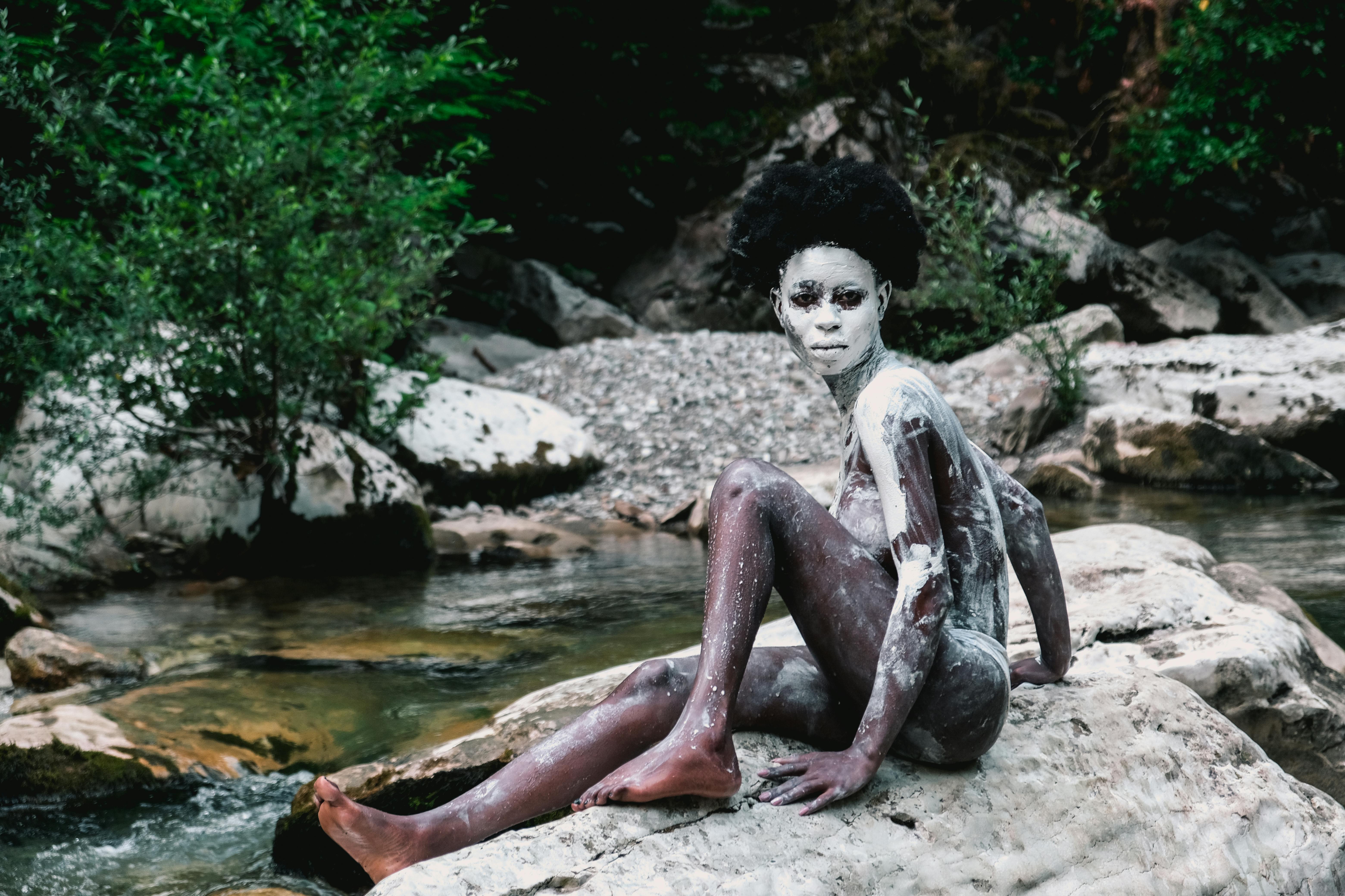 Naked Black Woman with Body Paint Sitting on Rock · Free Stock Photo