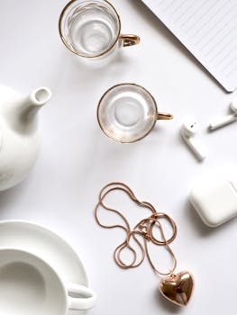 极简主义平铺搭配黄金珠宝、玻璃杯和白茶具，非常适合奢华生活方式主题