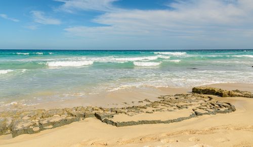 Free Peaceful sandy beach with gentle waves under a blue sky. Stock Photo