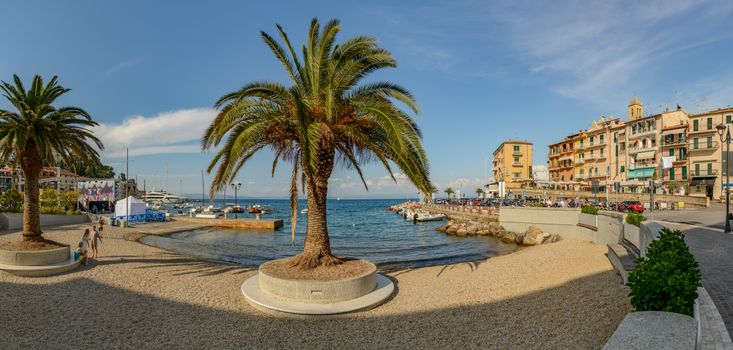 Beautiful seaside view of a Mediterranean town with palm trees and clear skies, perfect for travel and vacation.