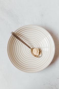 A minimalist presentation of one dumpling on a modern plate with a spoon, captured from above.