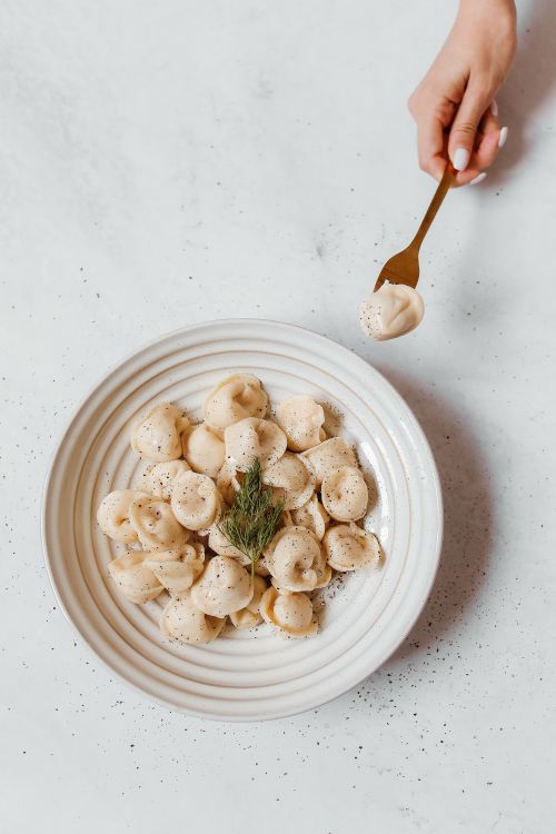 Free A delicious serving of Russian pelmeni with garnish on a ceramic plate, styled in a modern flat lay. Stock Photo