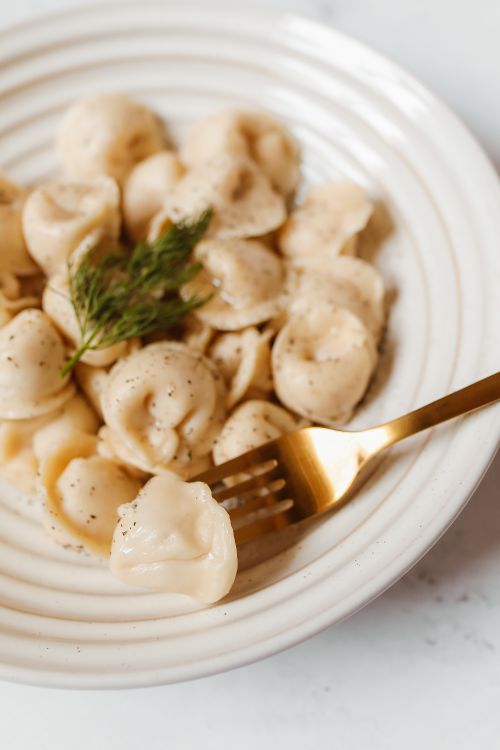 Free Close-up of traditional Russian pelmeni with dill, pepper, and a golden fork. Stock Photo