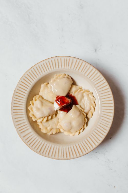 Free Top view of fresh dumplings served with strawberry jam on a decorative plate. Stock Photo