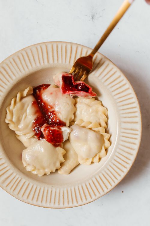 Free Top view of gourmet ravioli topped with berry sauce on a ceramic plate, perfect for food enthusiasts. Stock Photo