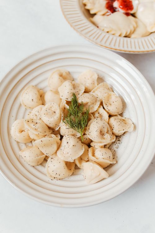Free Close-up of traditional Russian pelmeni sprinkled with herbs on a white plate, showcasing a classic dish. Stock Photo