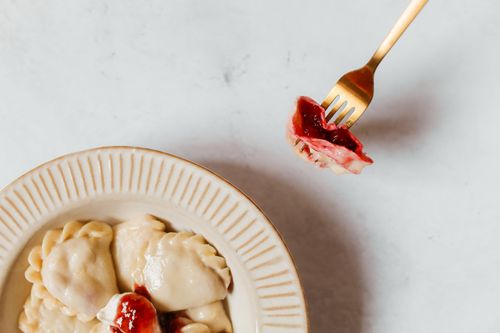 Free Tasty vareniki with berry filling on a fork and in a plate, showcasing Eastern European cuisine. Stock Photo