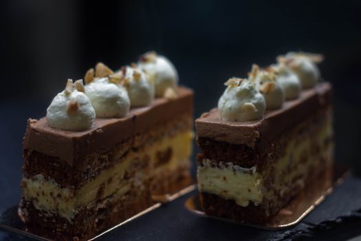 Indulgent chocolate mousse cake slices topped with whipped cream and nuts.