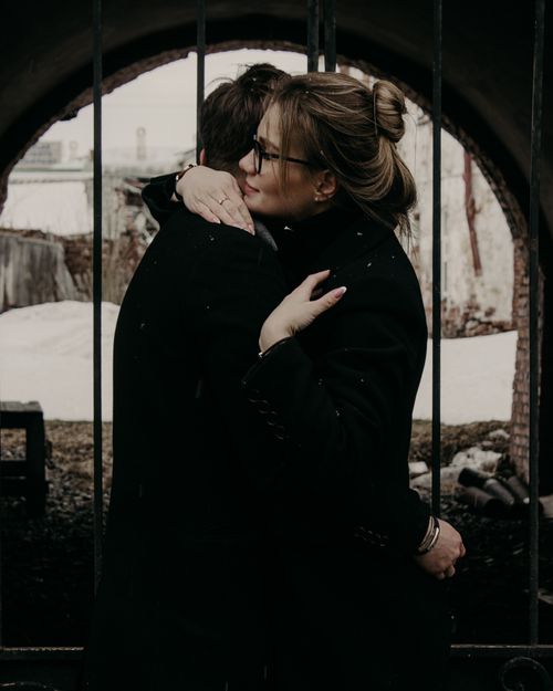 Free A couple embraces warmly outdoors against a rustic background in winter, conveying love and intimacy. Stock Photo