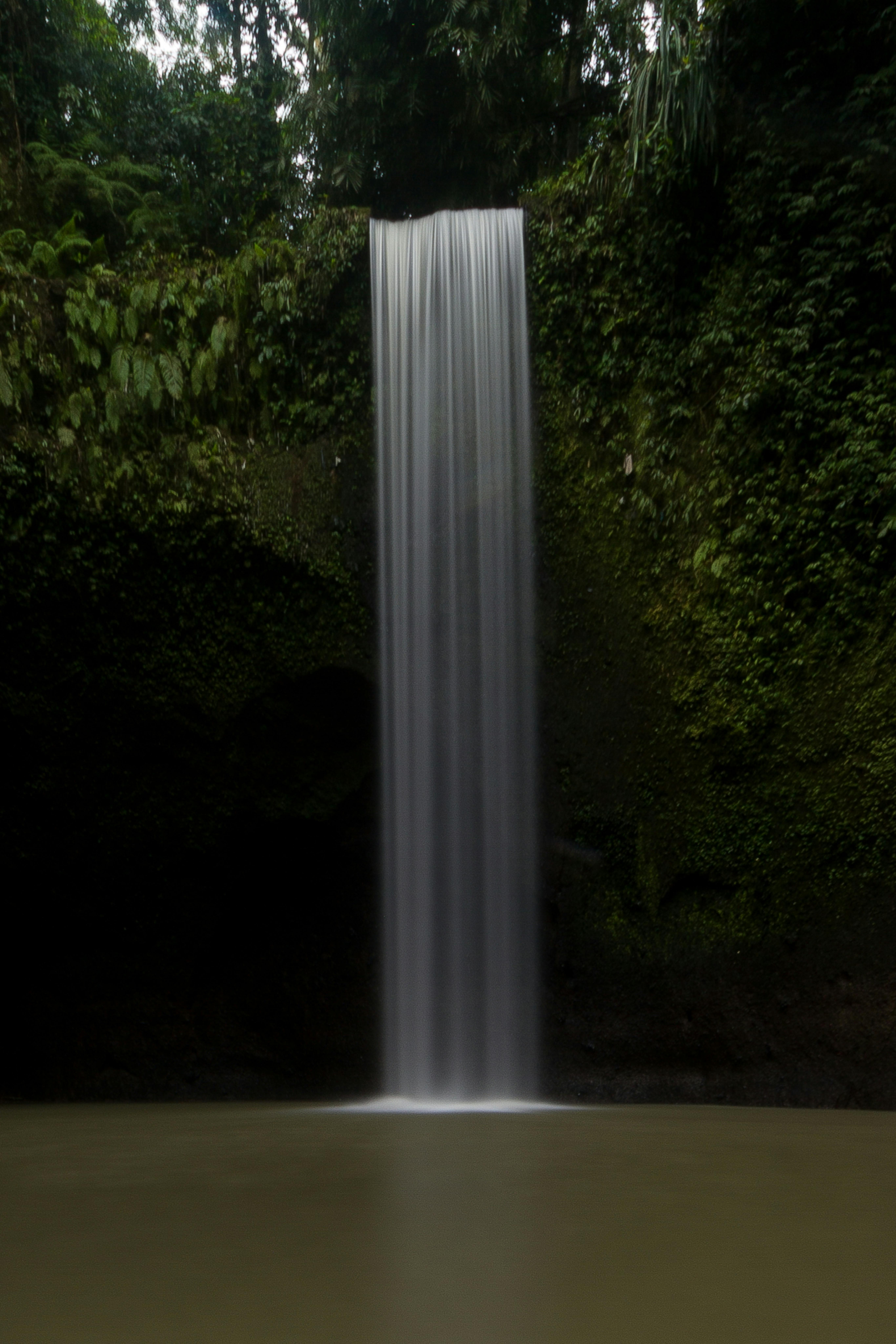 Captivating long exposure shot of a waterfall surrounded by vibrant forest foliage, perfect for nature lovers.
