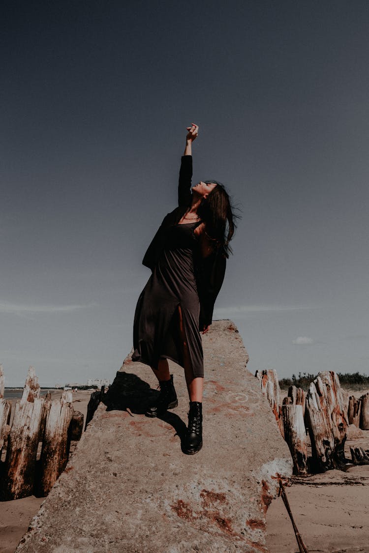 Woman In Black Clothes Raising Her Hand Standing On A Rock