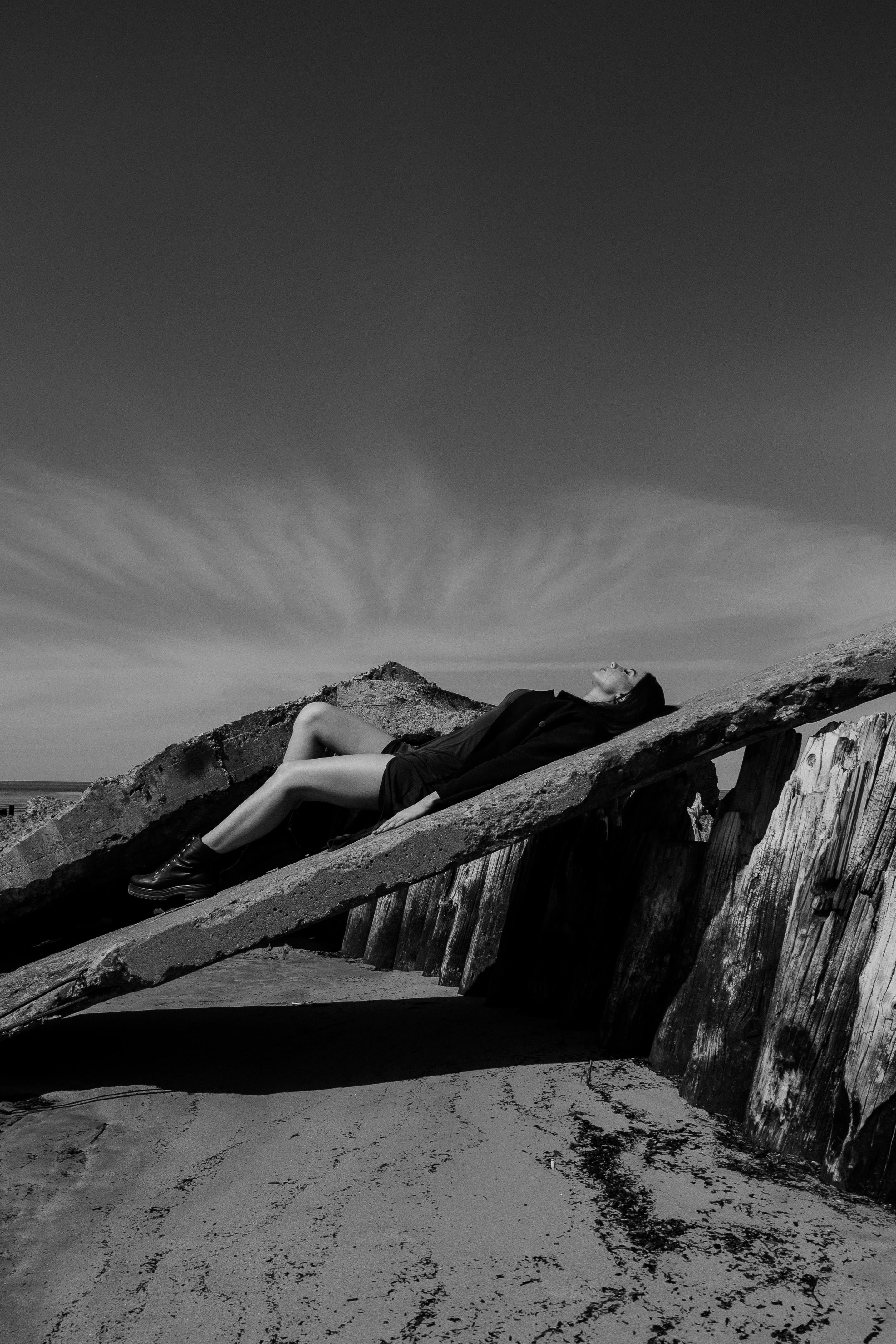 Artistic monochrome photo of a woman lying on a rock, capturing solitude.