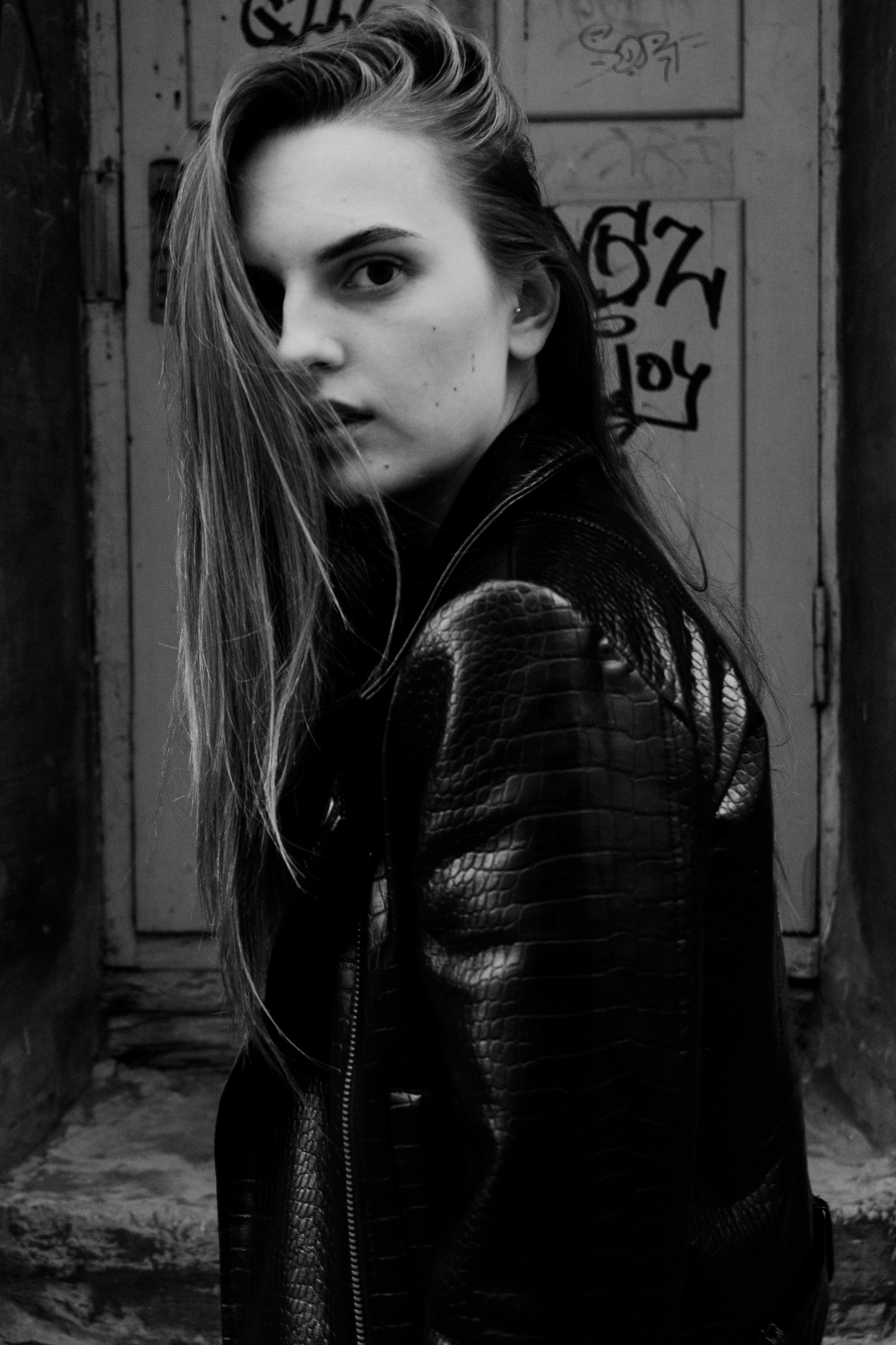 Intense black and white portrait of a woman wearing a leather jacket with an urban backdrop.