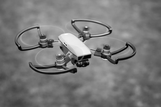 Monochrome image of a quadcopter drone in flight, showcasing modern technology.