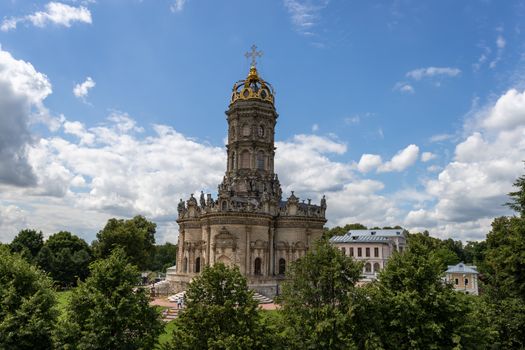 Znamenskaya Church in summer, framed by lush green trees and a bright blue sky.