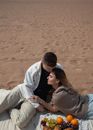Man in Gray Hoodie and Woman in Gray Hoodie Sitting on Brown Sand