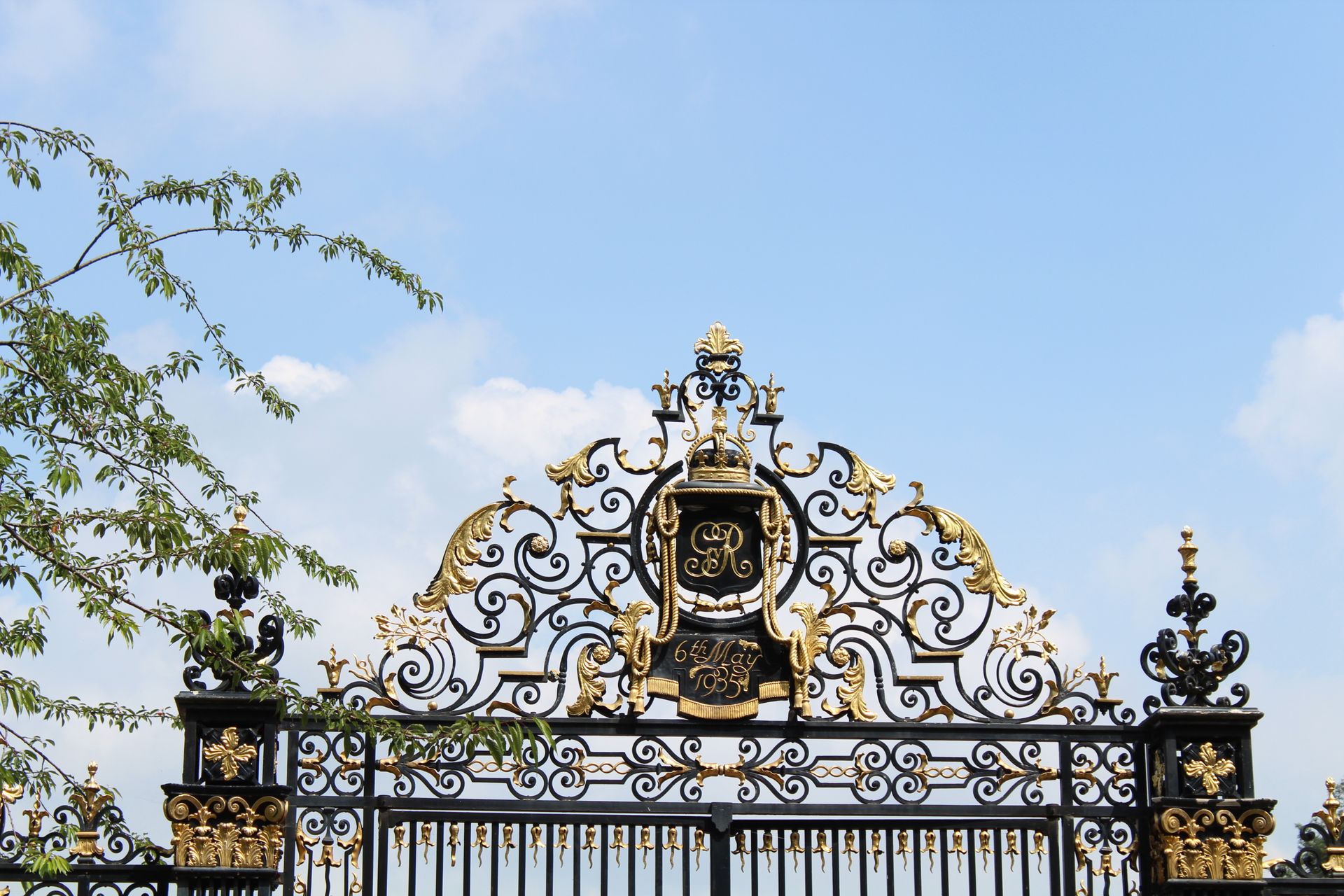 Elegant wrought iron gate with gold accents in Regent's Park, London, under a clear blue sky.