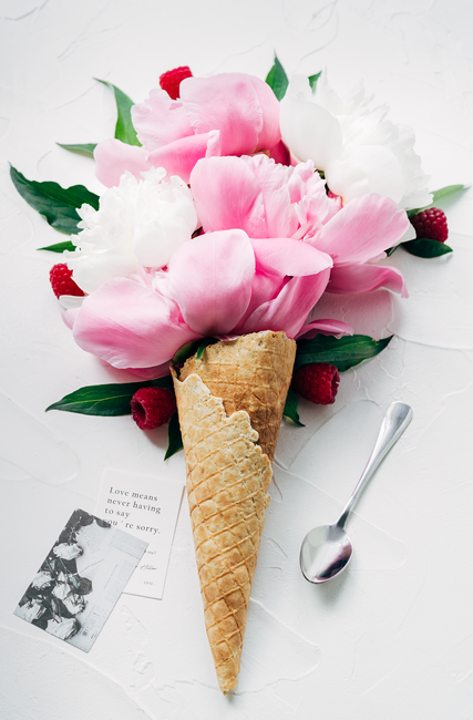 Creative flower arrangement in ice cream cone style with peonies and raspberries, top view.