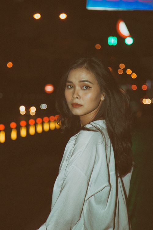 Free Elegant woman in white blouse posing on a city street at night. Stock Photo
