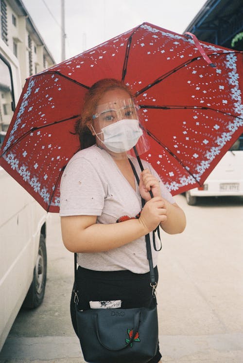 A Woman with Face Mask Holding a Red Umbrella