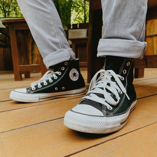 Free Close-up of black Converse sneakers with white laces on a wooden floor indoors. Stock Photo