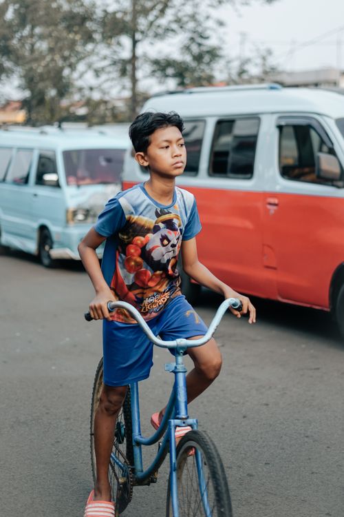 Free A young boy confidently rides his bicycle on a busy urban street, showcasing everyday life. Stock Photo