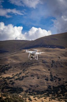 Aerial view of a drone flying over the scenic Andes Mountains under a clear blue sky.