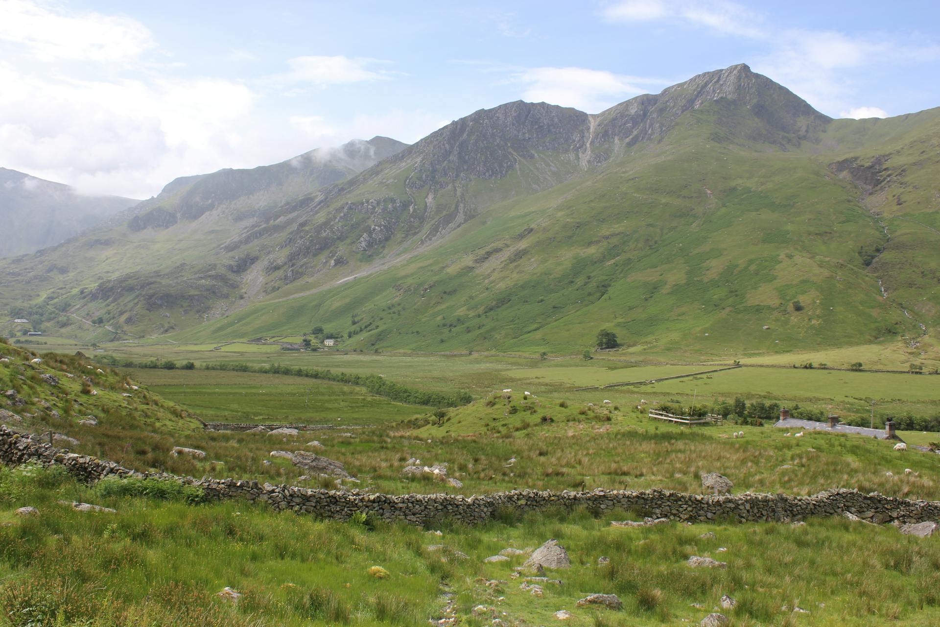 Scenic landscape of Snowdonia in Wales showcasing lush green valleys and towering mountains under a blue sky.