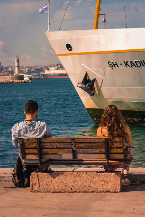 Free A couple sitting on a bench by the sea, overlooking a ferry in İstanbul, Türkiye. Stock Photo
