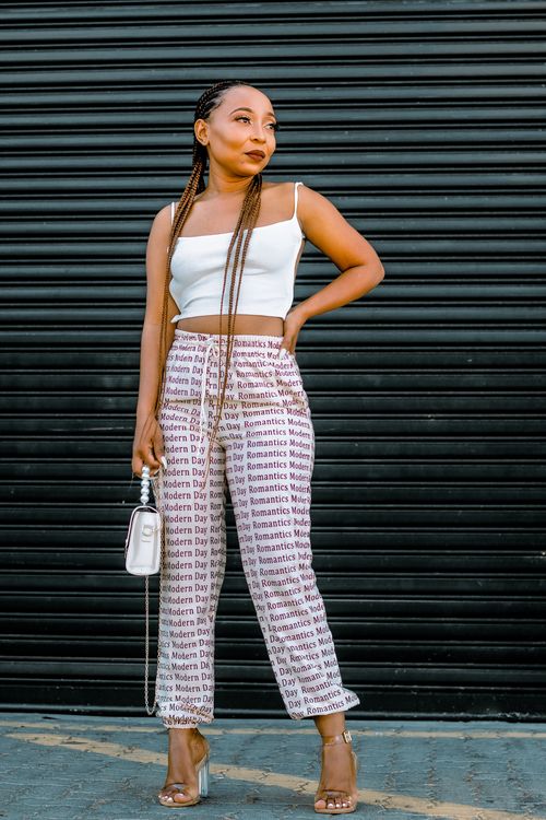 Free Fashionable young woman with braids and a crop top posing confidently outdoors. Stock Photo