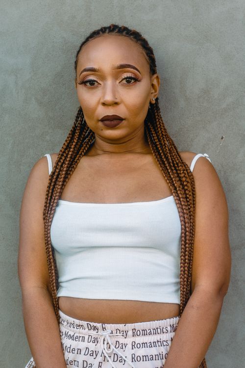 Free Stylish portrait of a woman with braided hair, wearing a white crop top and makeup. Stock Photo