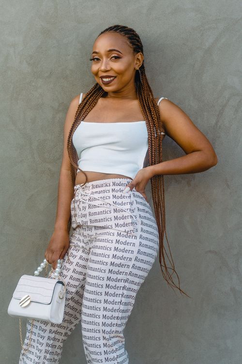 Free Fashionable woman with braided hair poses in trendy outfit against textured wall. Stock Photo