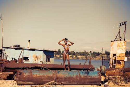 İki Parçalı Bikini Giyen Kahverengi çelik Konteyner üzerinde Duran Kadın