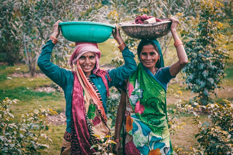 Two Women Wearing Traditional Dress Carrying Basins