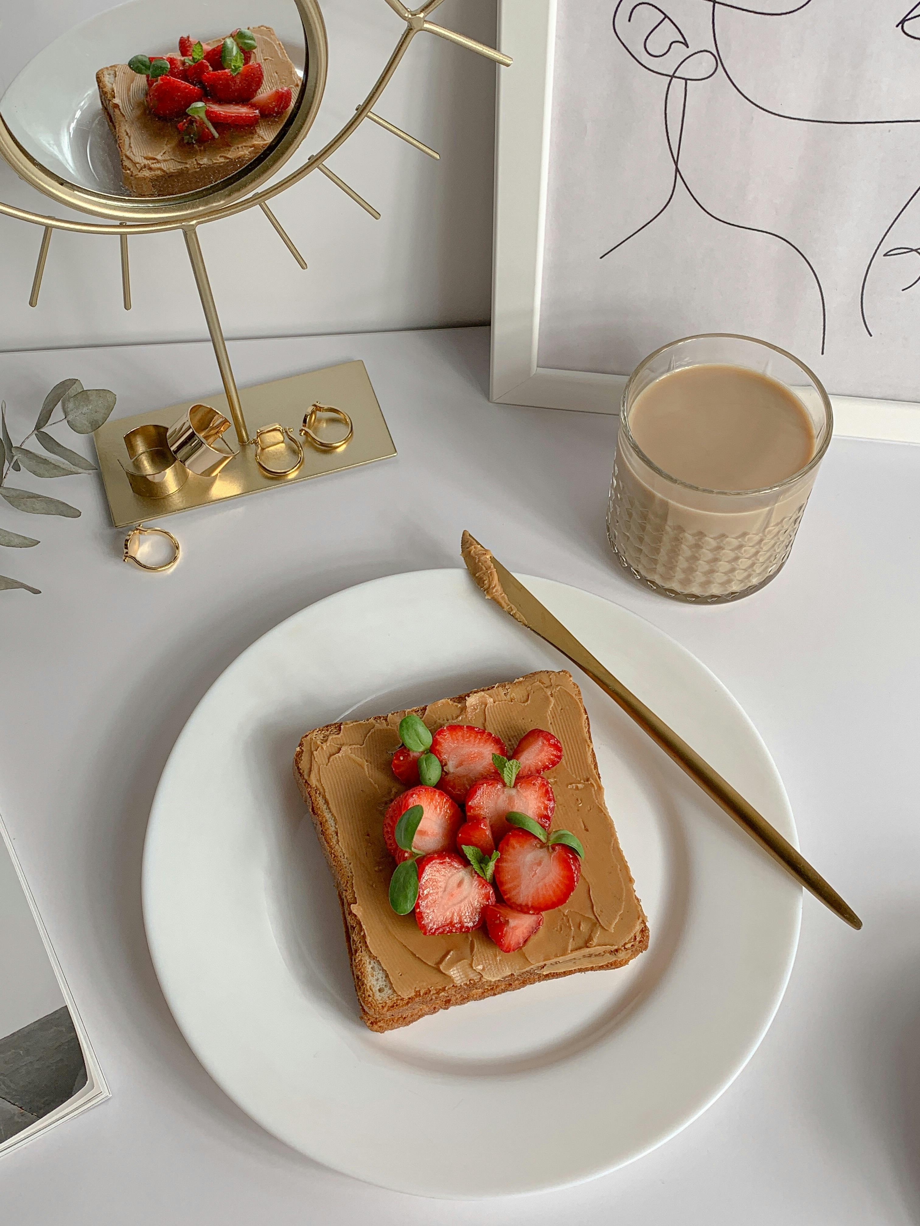 close up shot of a bread on a white plate beside a glass of beverage