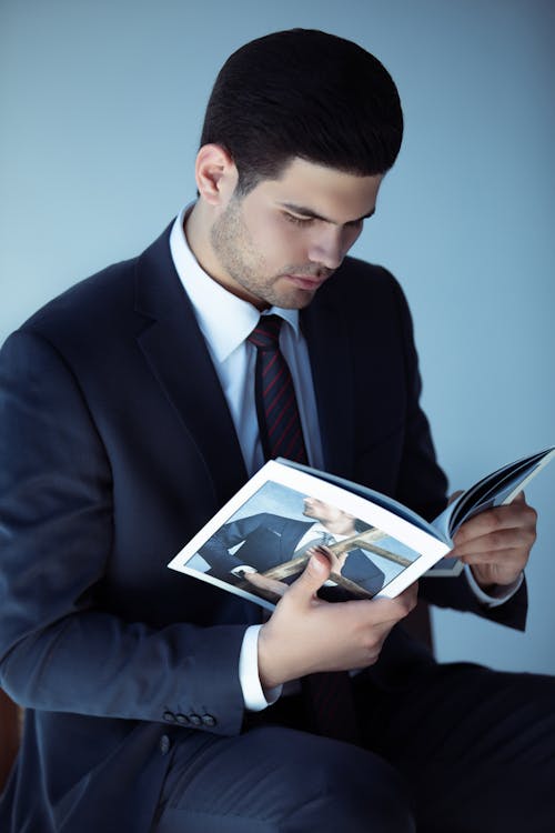 A Handsome Man in Black Suit Reading a Book